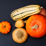 Organic Autumn food concept assortment vegetables Pumpkins, sweet potatoes, Delicata Squash, yellow turnip on black background